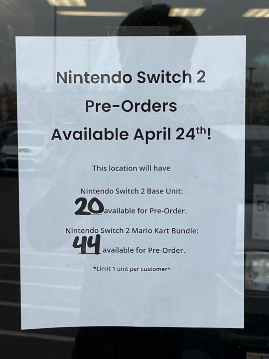 A printed sign on a glass door indicating how many consoles will be available for preorder